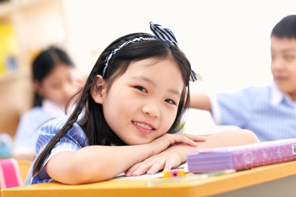 Captivating image of a young Asian girl smiling in a classroom environment.